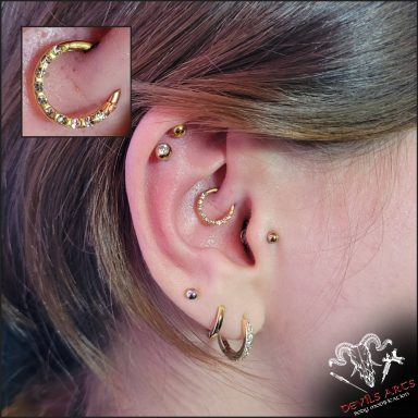 Daith-Piercing mit goldenem Kristall-Clicker am Ohr.