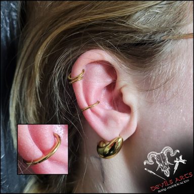 Innerconch-Piercing mit goldenem Segmentring-Clicker am Ohr.