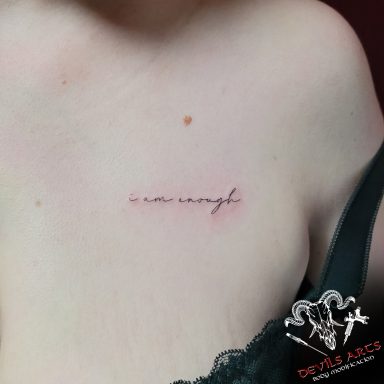Feines Schriftzug-Tattoo „I am enough“ im Brustbereich, gestochen im DEVILS-ARTS Studio.