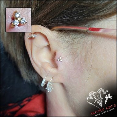 Tragus-Piercing mit goldener Kristall-Blume am Ohr.