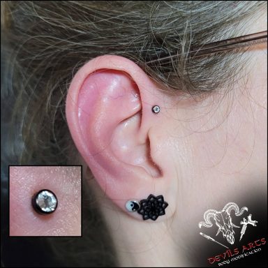 Forward-Helix-Piercing mit schwarzer Kristallplatte am Ohr.