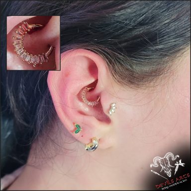 Daith-Piercing mit goldenem Kristall-Clicker am Ohr.
