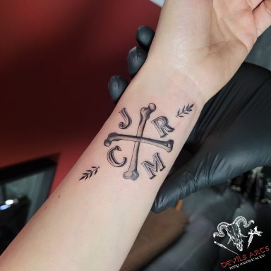Frank Turner inspiriertes Familien-Tattoo am Handgelenk mit Initialen und gekreuzten Knochen.