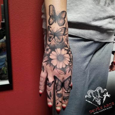 Black & Grey Hand-Tattoo Black & Grey Handtattoo mit Blumen- und Schmetterlingsmotiv auf Hand und Unterarm, gestochen im DEVILS-ARTS Studio.