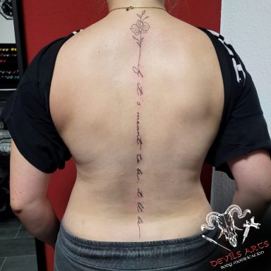 Wirbelsäulen-Tattoo Schriftzug mit Blume Wirbelsäulen Schriftzug Tattoo mit Blumenmotiv in Fineline entlang der Wirbelsäule.