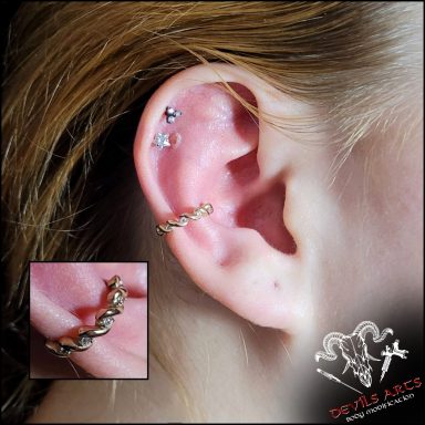 Innerconch-Piercing mit gedrehtem, goldenem Kristall-Clicker am Ohr.