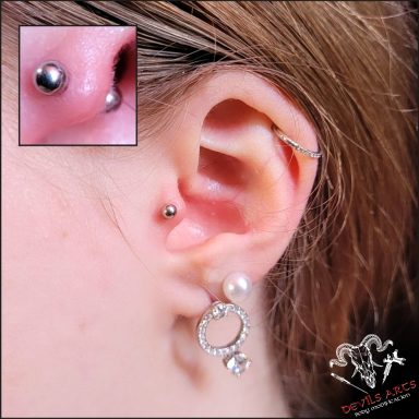Tragus-Piercing mit silbernem Barbell am Ohr.